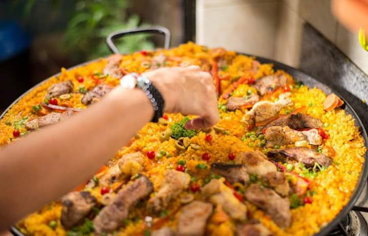 A paella being finished by hand at an event