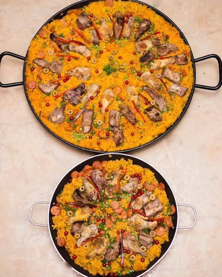 Two large paella pans prepared for a catered gathering