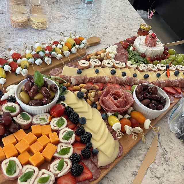 A large grazing table with cheeses, meats, olives, and fruit