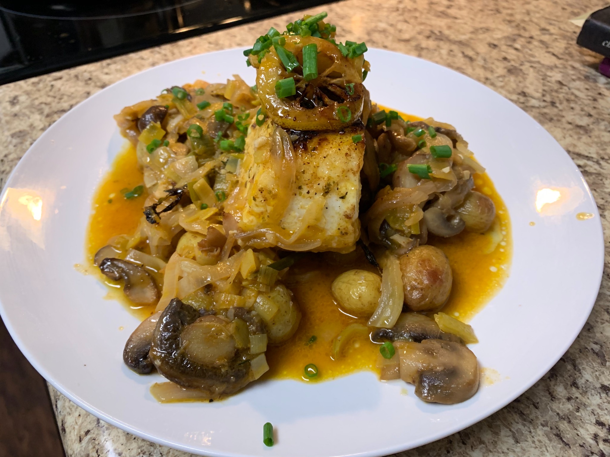 Plated corvina with mushrooms, potatoes, and a golden sauce